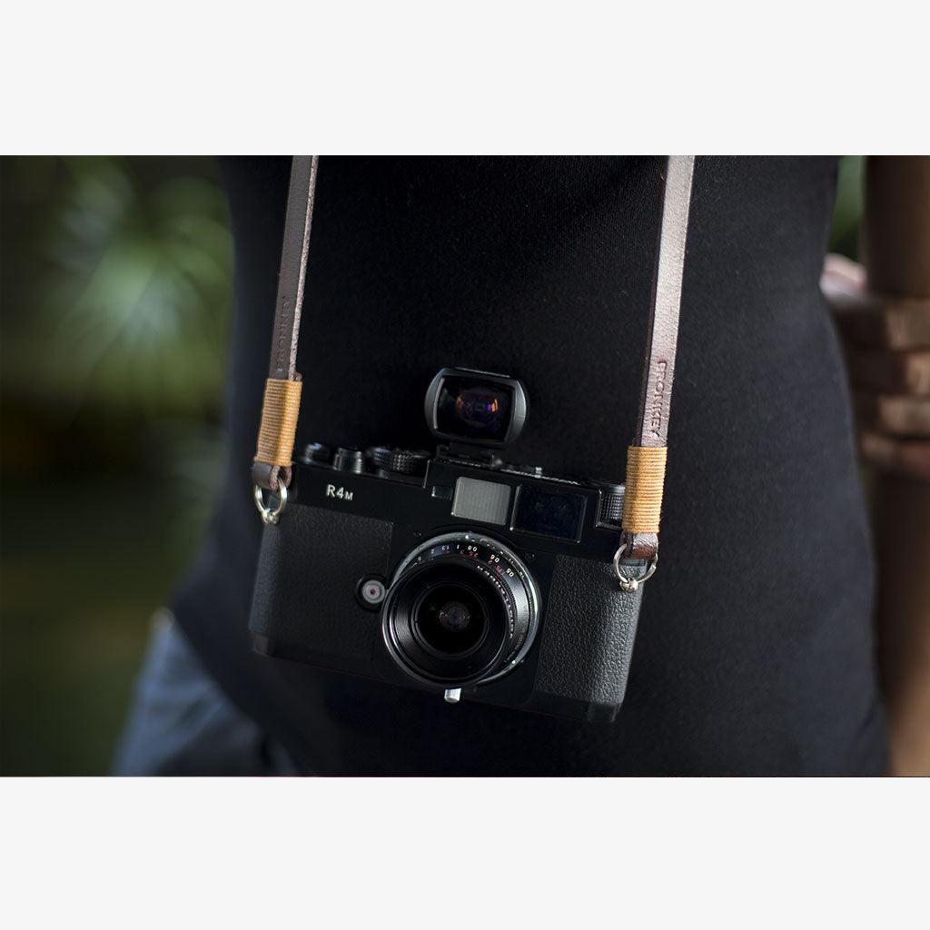 Handmade full-grain leather camera strap attached to a mirrorless camera